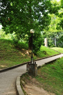 Parkın arka sokağı, taşla kaplı. Parkın manzarası, fener ve ağaçlar..