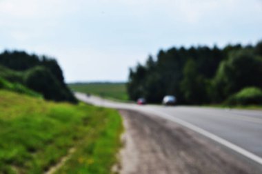 Bulanık yol geçmişi. Odak noktası yok, arabalar yol boyunca ağaçlar. Arkaplan, doku, bokeh.