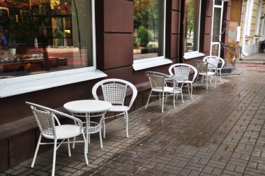 Evin etrafında bir sıra beyaz masa ve sandalyeler. Yazlık kafe masaları. 02 Eylül 2021, Orel, Rusya.