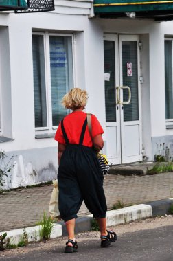 Alışverişi olan bir kadın şehir caddesinde yürüyor. Şehir hayatının resmi..