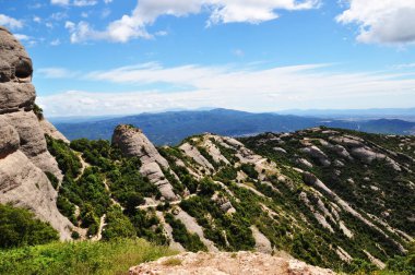 Dağların panoramik manzarası. Dağlar ender ormanlarla kaplıdır. Mavi gökyüzündeki bulutlar. Arkaplan, doku, manzara.