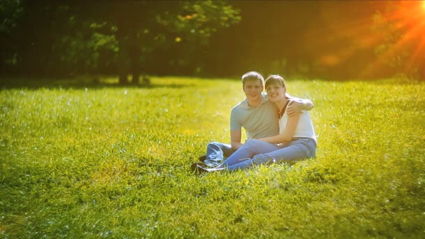 Pareja joven sentada en la hierba — Vídeos de Stock