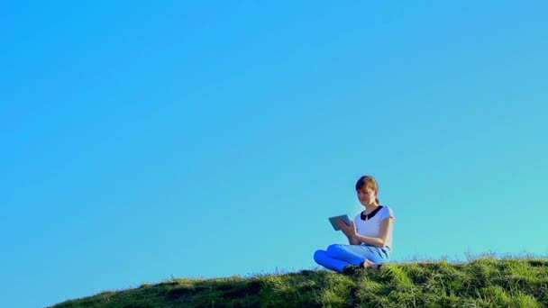 Mladá žena sedí na kopci — Stock video