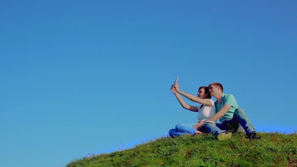 Молодая любящая пара сидит на траве — стоковое видео