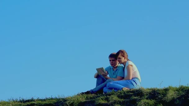 Молодая любящая пара сидит на траве — стоковое видео