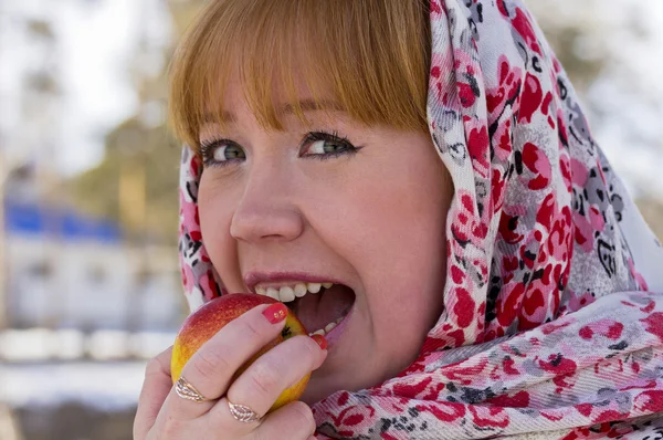 Mädchen in buntem Schal isst einen Apfel. — Stockfoto