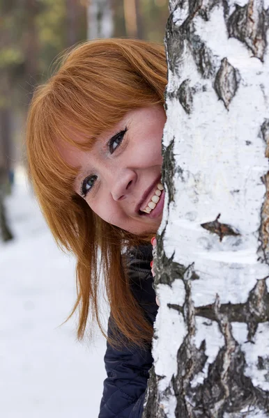 Das Mädchen lugt hinter der Birke hervor. — Stockfoto