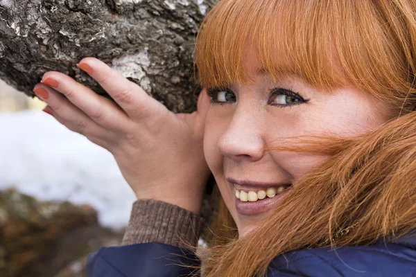 Rothaariges Mädchen berührt die Rinde einer Birke. — Stockfoto