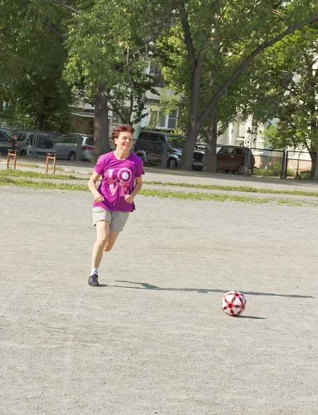 Egy idős asszony fut át a játszótér, a futball-labda — Stock Fotó