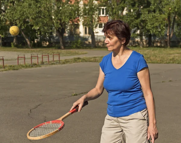 Um atleta idoso treina com uma raquete e uma bola de tênis . — Fotografia de Stock