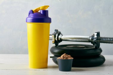 a scoop with protein powder near shaker and barbel