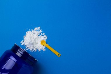 Mavi arkaplan fotokopi alanı üzerine spor takviyesi kreatin tozu