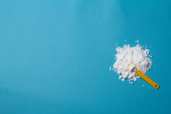 sports supplement creatine powder on pale blue background copy space