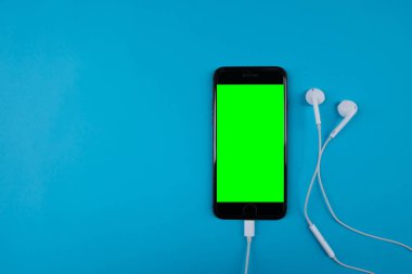 Mavi arka planda akıllı telefon ve kulaklıklar - yeşil ekran