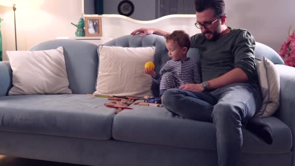 Πατέρας Και Χαριτωμένο Αγοράκι Κάθεται Στον Καναπέ Στο Σπίτι Παίζοντας — Αρχείο Βίντεο