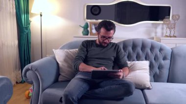 Evde dijital tablet kullanan yakışıklı adam