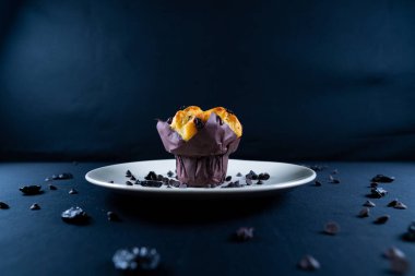 Çikolata, üzümlü cips ve beyaz tabakta kuru üzümlü kek. Siyah arka plan. Kopyalama alanı