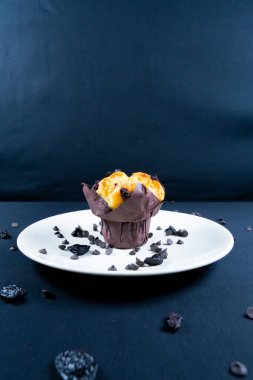 Çikolata, üzümlü cips ve beyaz tabakta kuru üzümlü kek. Siyah arka plan. Kopyalama alanı