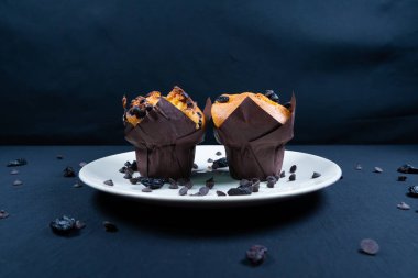 Çikolata, üzümlü cips ve beyaz tabakta kuru üzümlü kek. Siyah arka plan. Kopyalama alanı