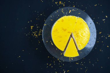 Siyah arka planda cam tabakta dilimlenmiş limonlu cheesecake. (Boşluk)