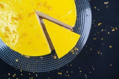 Siyah arka planda cam tabakta dilimlenmiş limonlu cheesecake. (Boşluk)