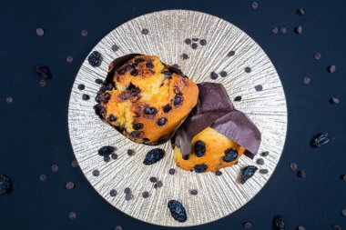 Çikolata, üzümlü cips ve beyaz tabakta kuru üzümlü kek. Siyah arka plan. Kopyalama alanı