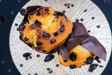 Çikolata, üzümlü cips ve beyaz tabakta kuru üzümlü kek. Siyah arka plan. Kopyalama alanı