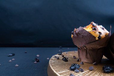 Çikolata, üzümlü cips ve beyaz tabakta kuru üzümlü kek. Siyah arka plan. Kopyalama alanı