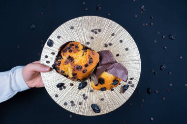 Tabakta çikolata ve üzümlü kek tutan bir kadın.