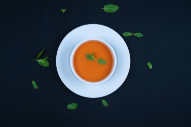 Fesleğenli domates çorbası ve kasede ekmek. Koyu arkaplan.