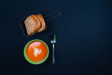 Fesleğenli domates çorbası ve kasede ekmek. Koyu arkaplan.