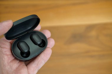 Elinde şarj çantası olan kablosuz kulaklıklar. Yakın çekim görüntüsü.