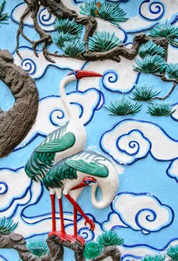 Bas relief sculpture of crane on the tree with cloud background clipart