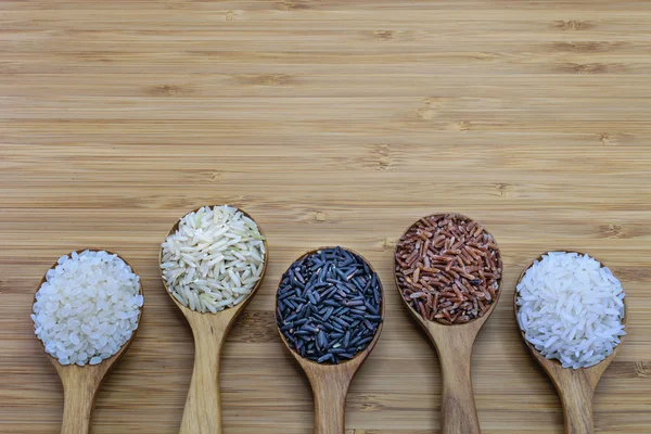 Odrůda rýže v dřevěné lžíce na pozadí neleštěná rýže a rýže leštěná — Stock fotografie
