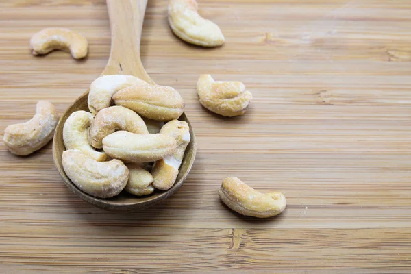 Cashews in spoon on wood background — Stock Photo, Image