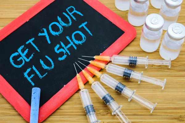 Get Your Flu shot written on chalkboard with vaccine in syringes — ストック写真