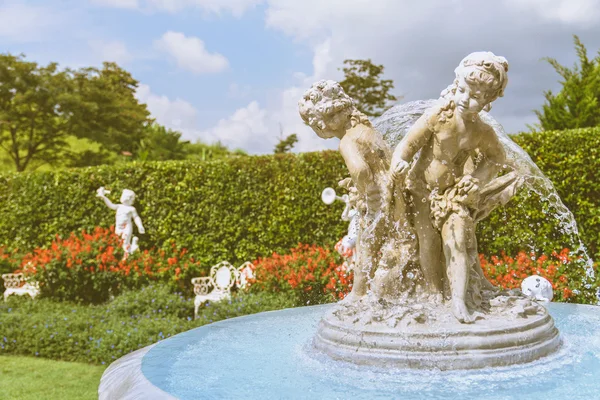 Young sculpture and fountain in the English garden, vintage style — Stock Photo, Image