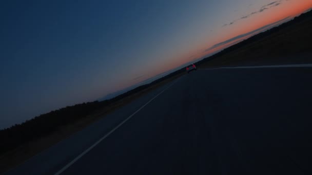 Un coche que conduce hacia el hermoso atardecer en un camino vacío. — Vídeos de Stock