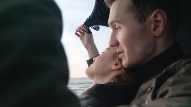 Szczęśliwa para stojąca i przytulająca się na zimnej, słonecznej plaży jesienią — Wideo stockowe