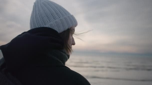 Девушка смотрит на закат на холодном красивом пляже — стоковое видео
