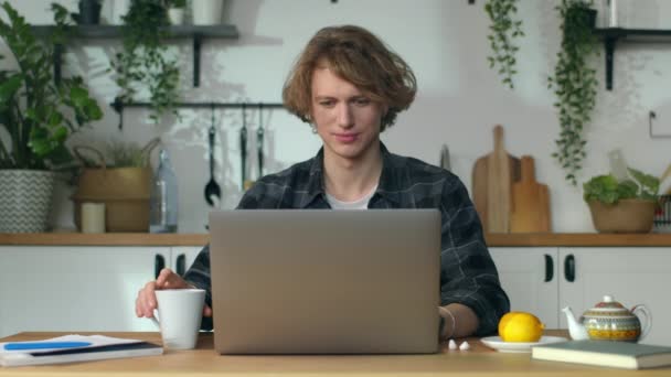 Freelancer trabaja en casa, el hombre bebe agua en la mesa detrás del cuaderno — Vídeos de Stock