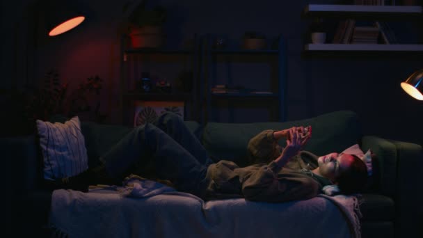 Flicka chatta med vänner med hjälp av sin telefon, kvinna vila på soffan på kvällen — Stockvideo