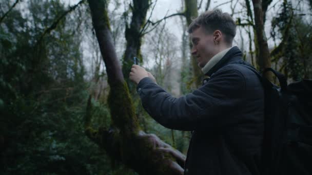 Young guy is taking photos in forest with phone, nature photography on phone — Stock Video