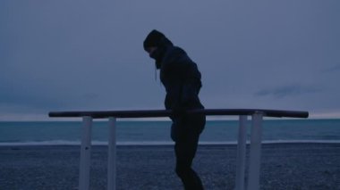 Genç uzun boylu insan spor yapıyor. Kötü havada açık havada antrenman yapmak