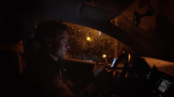 Stilig ung man gömmer sig från regnet och talar med någon med smartphone — Stockvideo