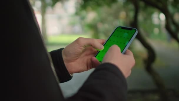 Close-up handen man met telefoon met verticaal groen scherm op park achtergrond — Stockvideo
