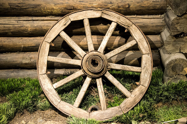 Old wooden coach wheel near barn