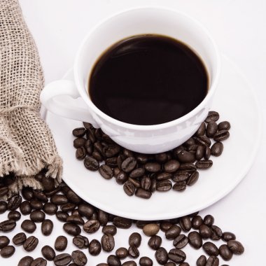 Beyaz arka planda kahve fincanı ve fasulye..