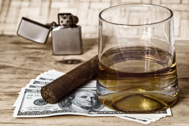 Bardak viski ve Küba purosu ile para.