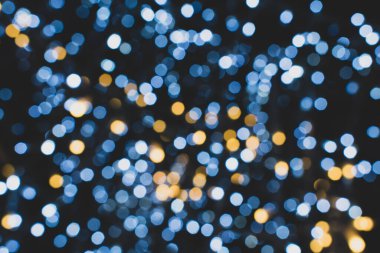 Noel ışıkları. Yeni yıl kutlamaları mavi, altın ve siyah arkaplanı bulanıklaştırdı. Güzel, ışıl ışıl bir arka plan, doku. Bokeh. Uzayı kopyala Mesaj için yer. Şablon. Moda gözlükleri. Xmas.